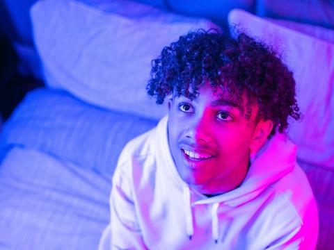 Virtual Work Experience header Young man looks up with a curious look, lit by a pink light