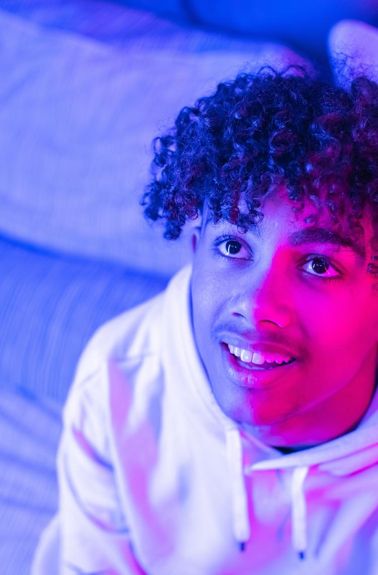 Virtual Work Experience header Young man looks up with a curious look, lit by a pink light